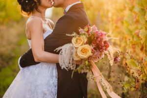 Autumn wedding photography in vineyard with golden light and floral bouquet.