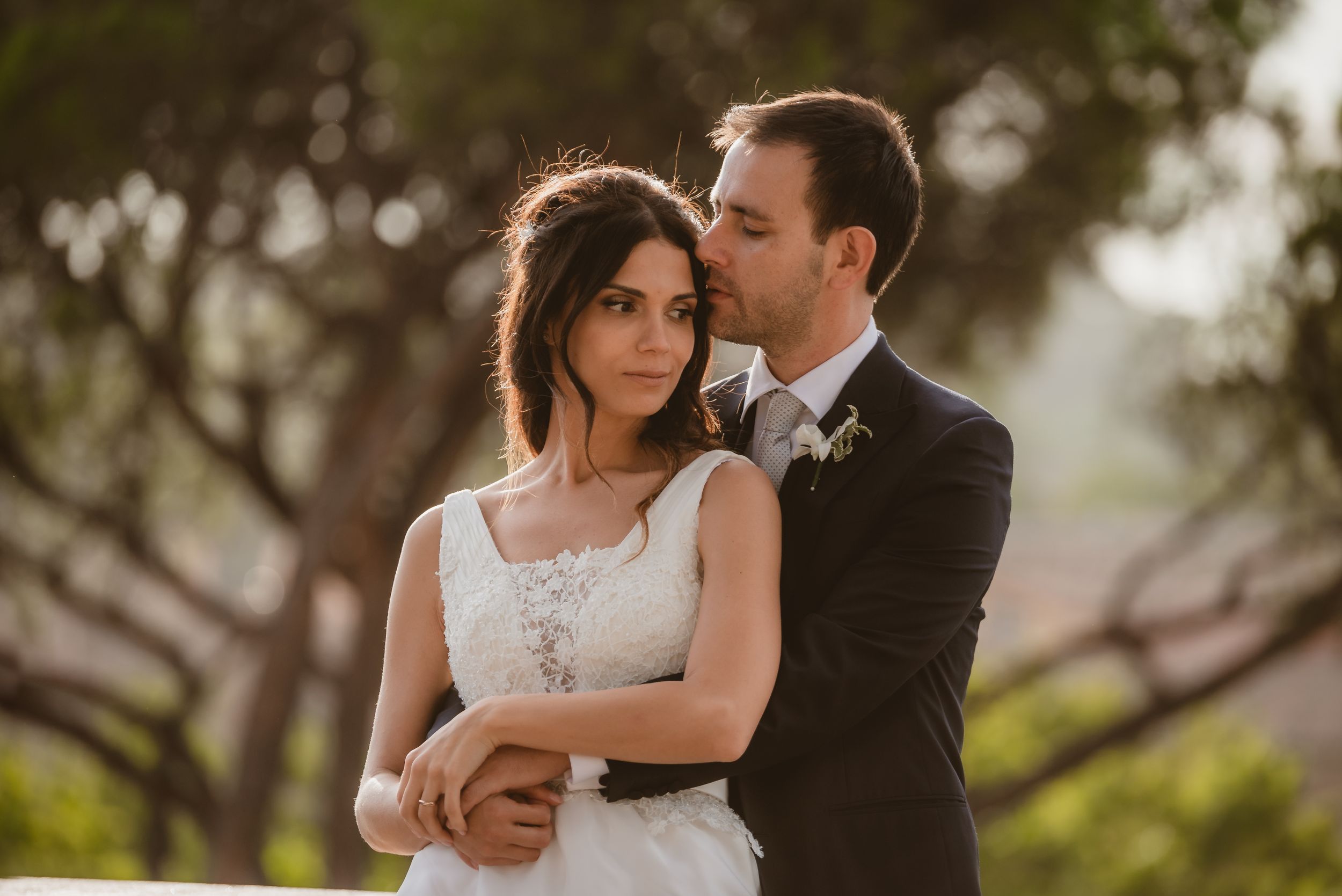 A tender moment between newlyweds embracing outdoors during golden hour.