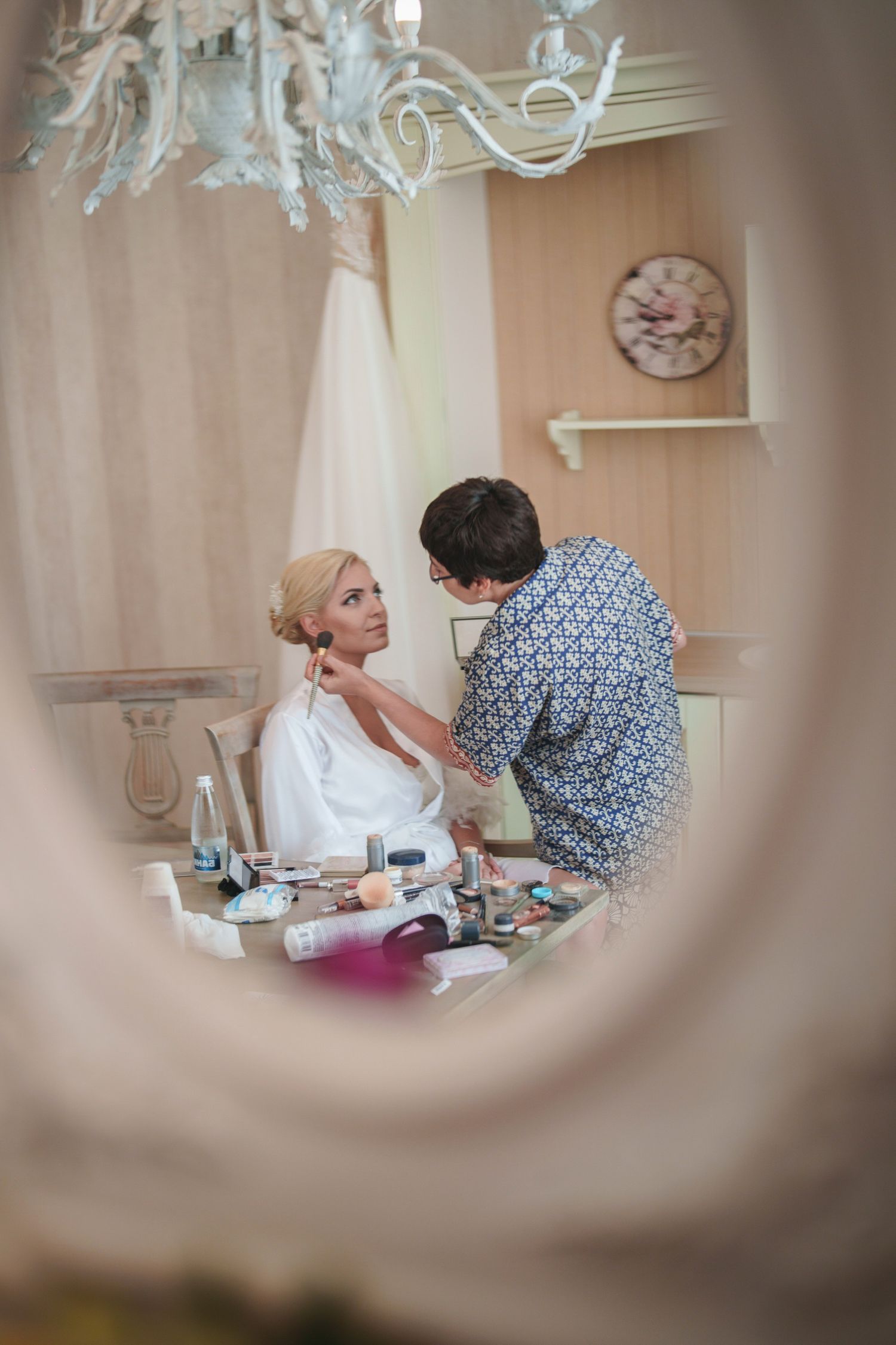 Getting ready scene viewed through decorative mirror frame.