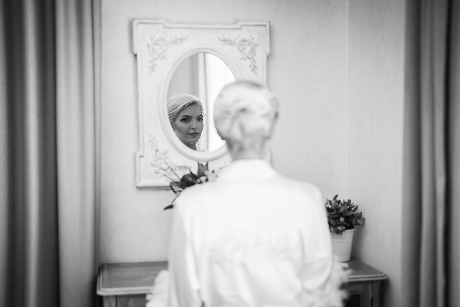 Black and white reflection of person in ornate vintage mirror.