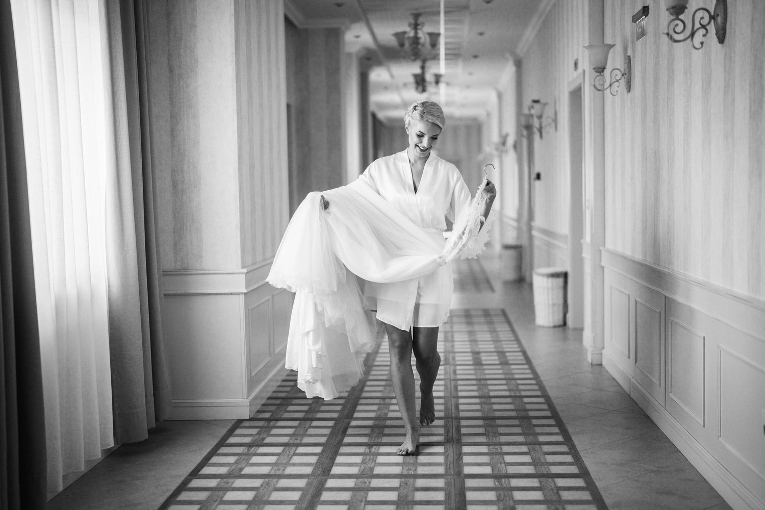 Someone running down an elegant hallway while carrying a white dress.