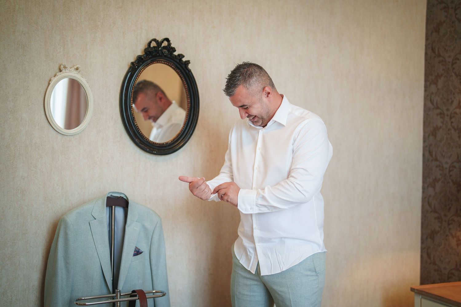 Getting ready scene with a light blue suit jacket hanging near a decorative mirror.