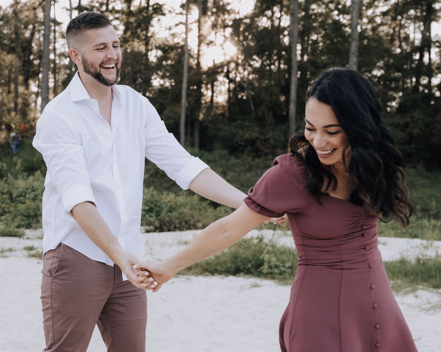 A playful couple in coordinated outfits dances together at sunset.