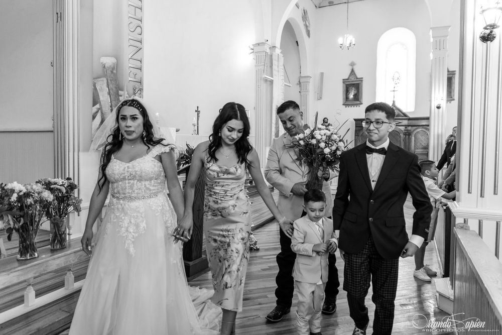 Wedding party walking through church hallway in formal attire.