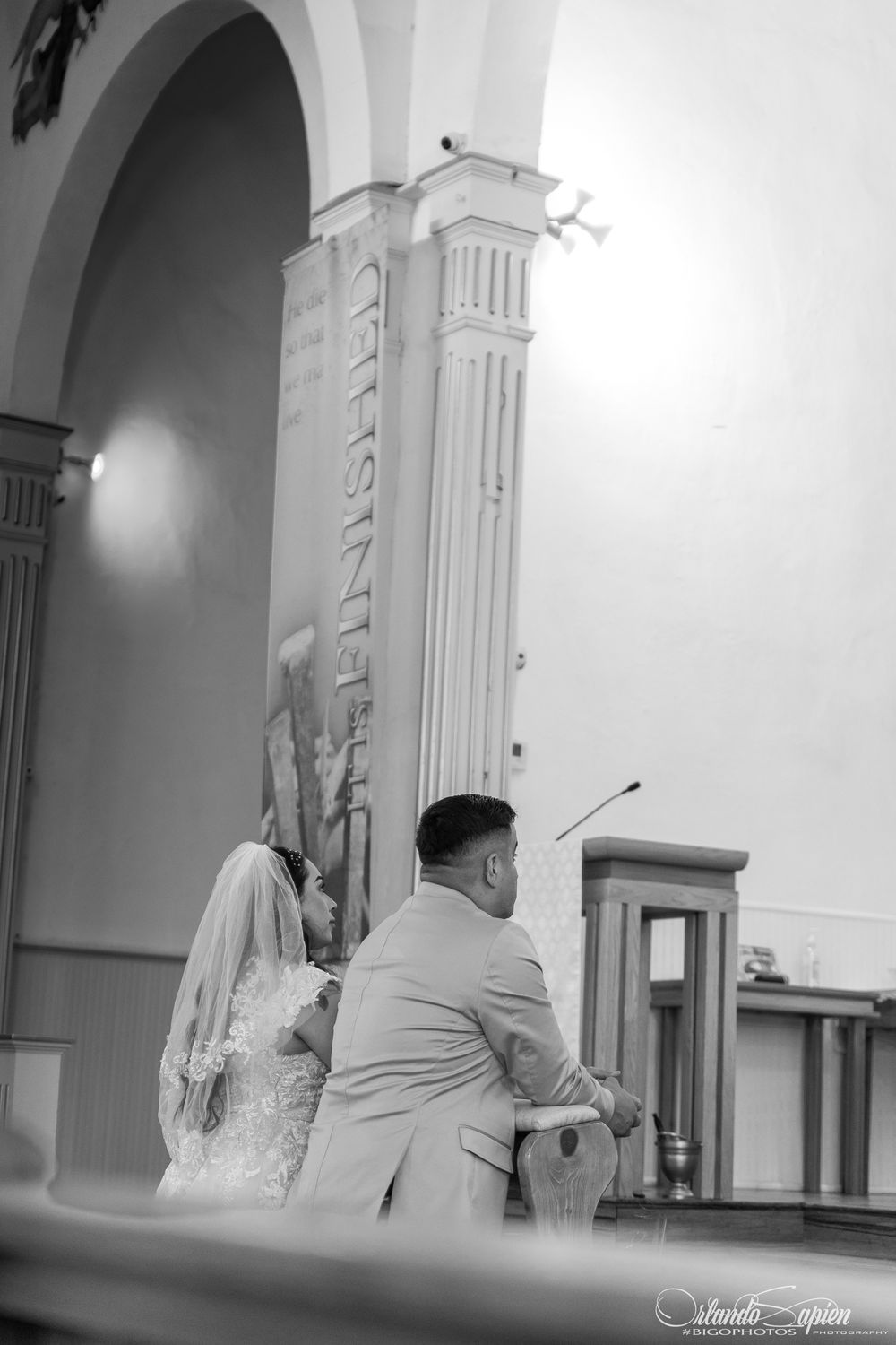 Black and white photo of wedding ceremony inside a church with arched architecture.