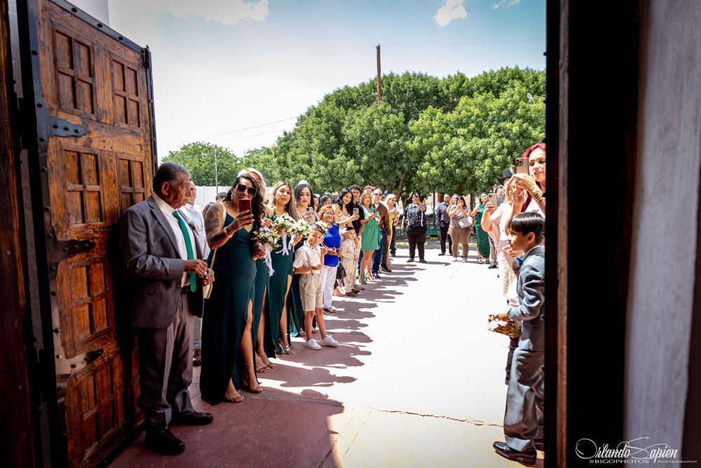 Wedding guests lined up along a hallway creating an aisle for the newlyweds to walk through.