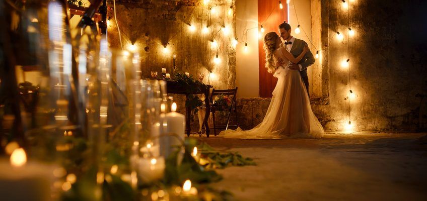 Romantic evening wedding scene illuminated by warm glowing candlelight with a couple embracing in the elegant venue.
