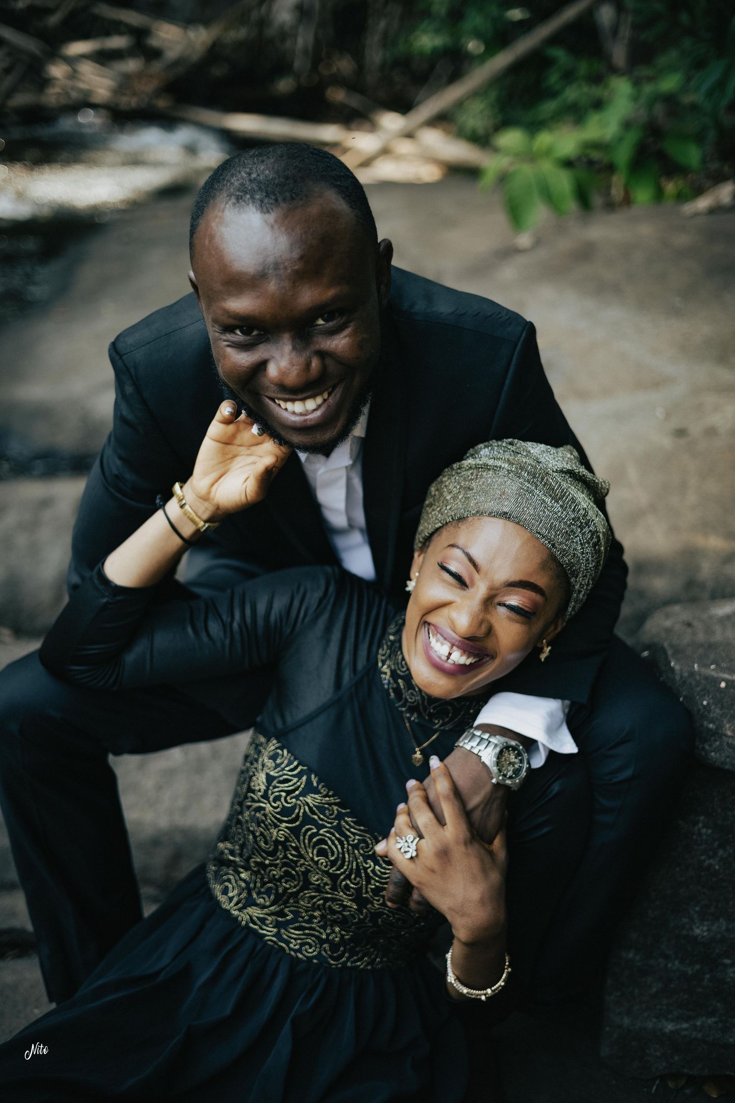 A joyful candid moment shared between two people in formal attire outdoors.