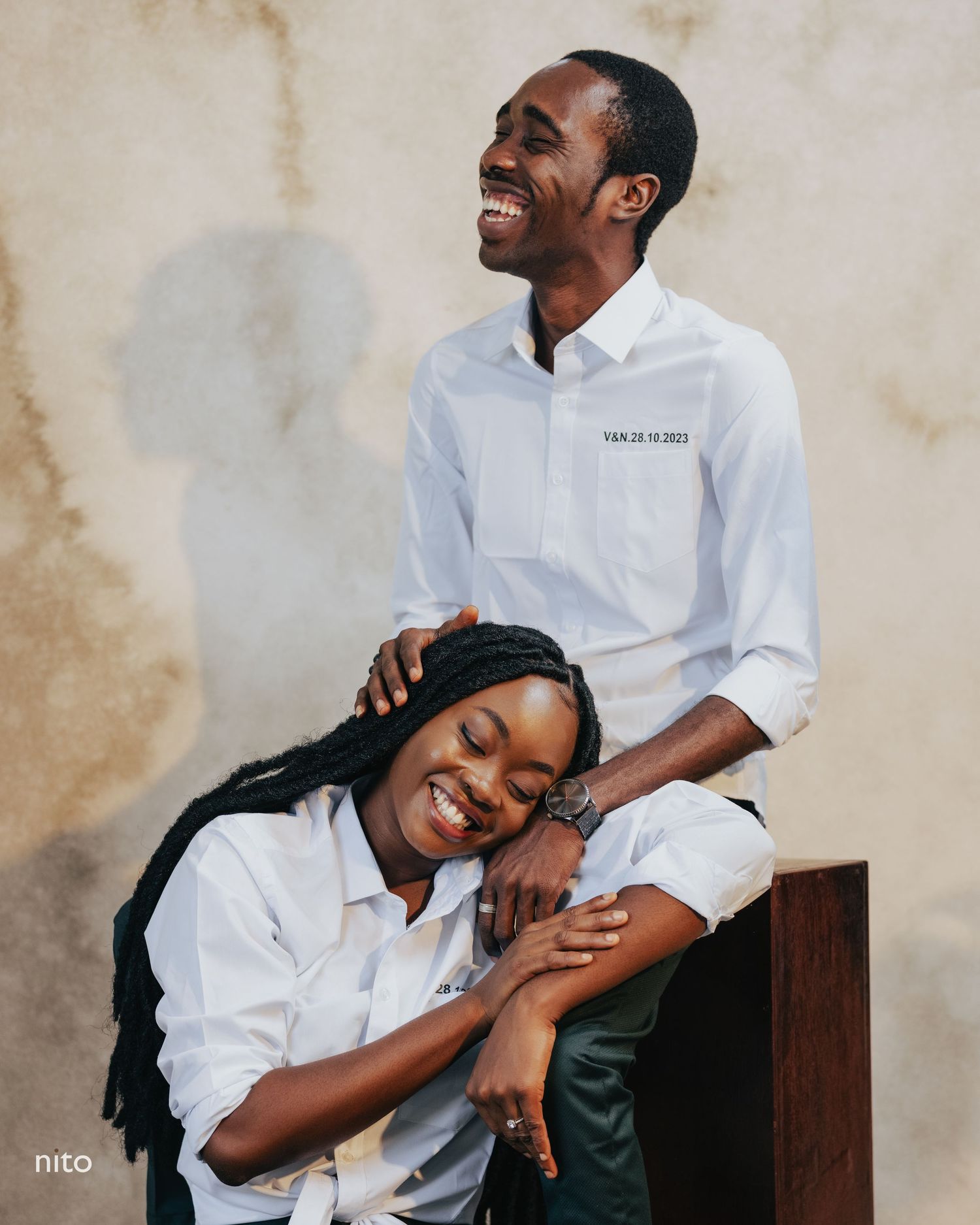 Couple in matching white shirts sharing a playful and intimate moment during a photoshoot.