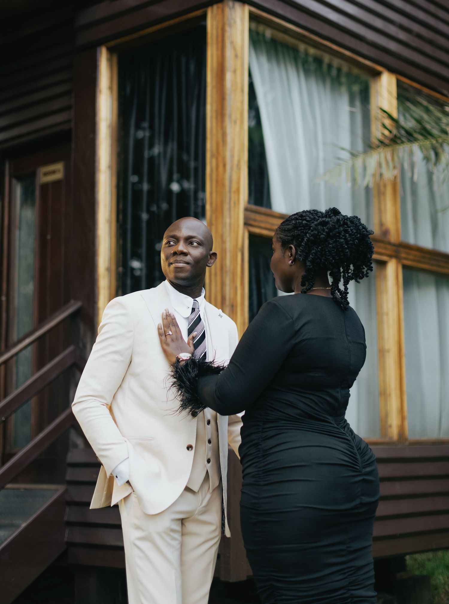 Wedding preparation moment with person in cream suit being helped with attire.