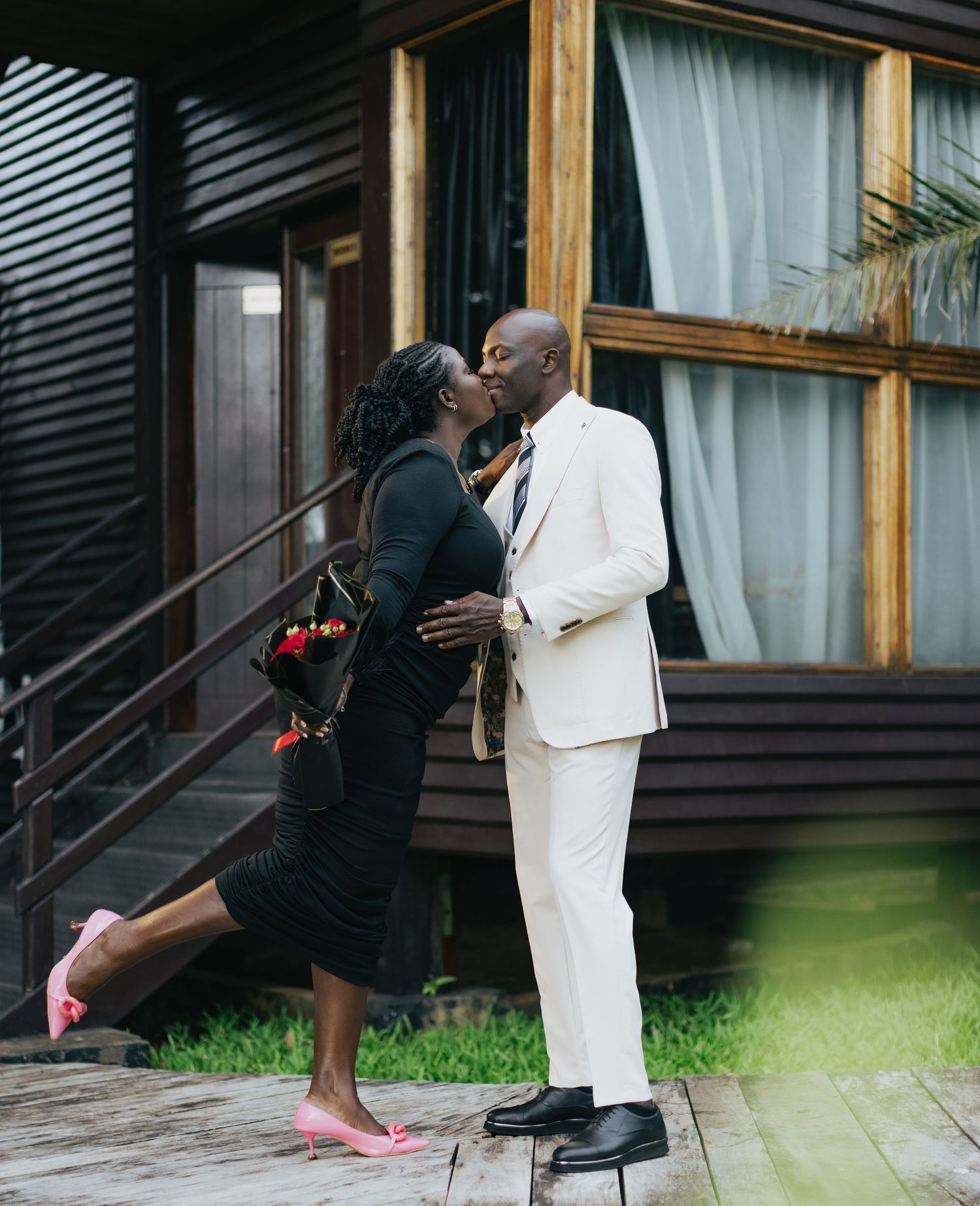 Romantic moment between couple on wooden deck, with formal black and white attire.