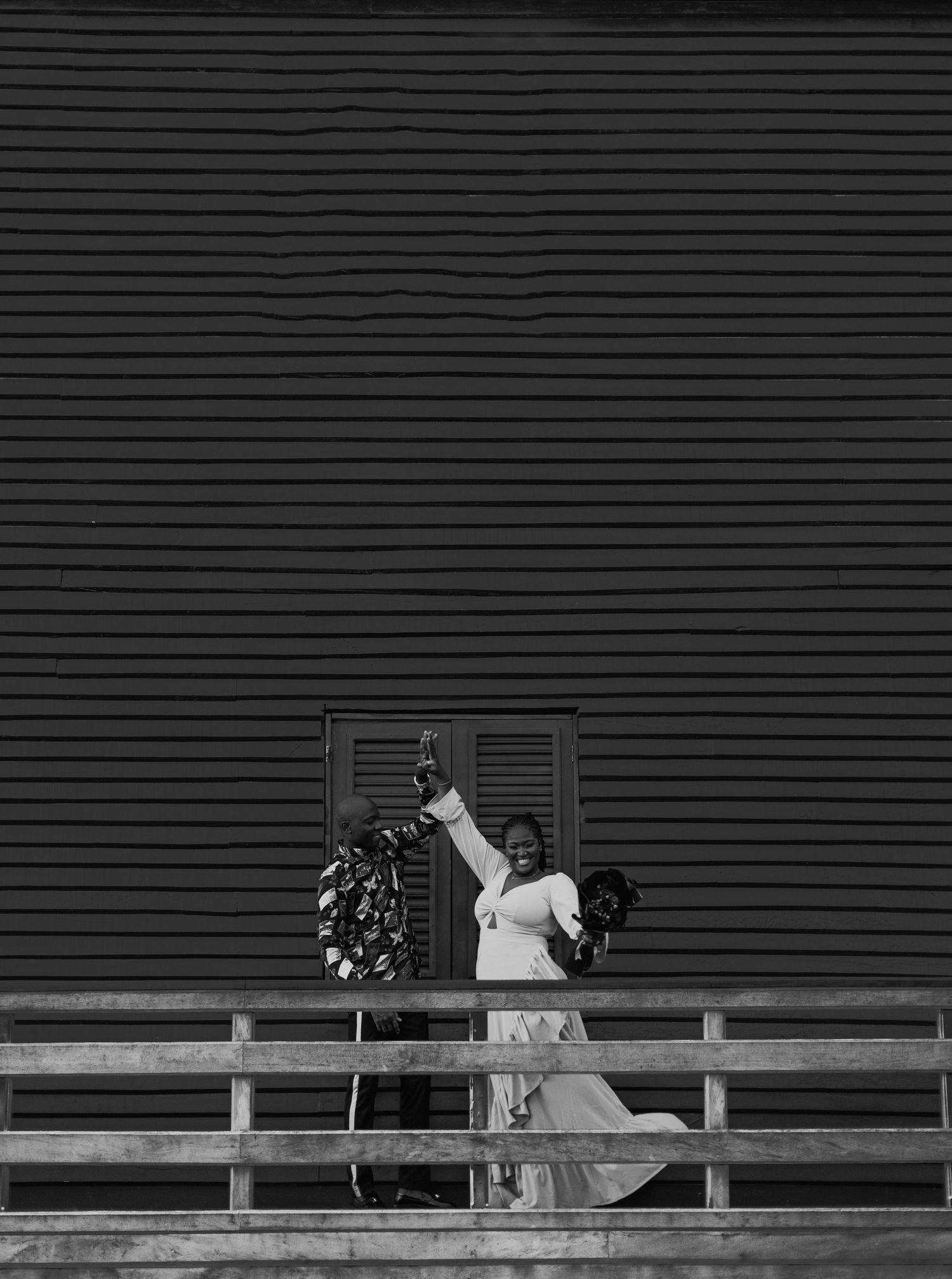 Black and white photo of someone in formal wear approaching a door with decorative wreath.