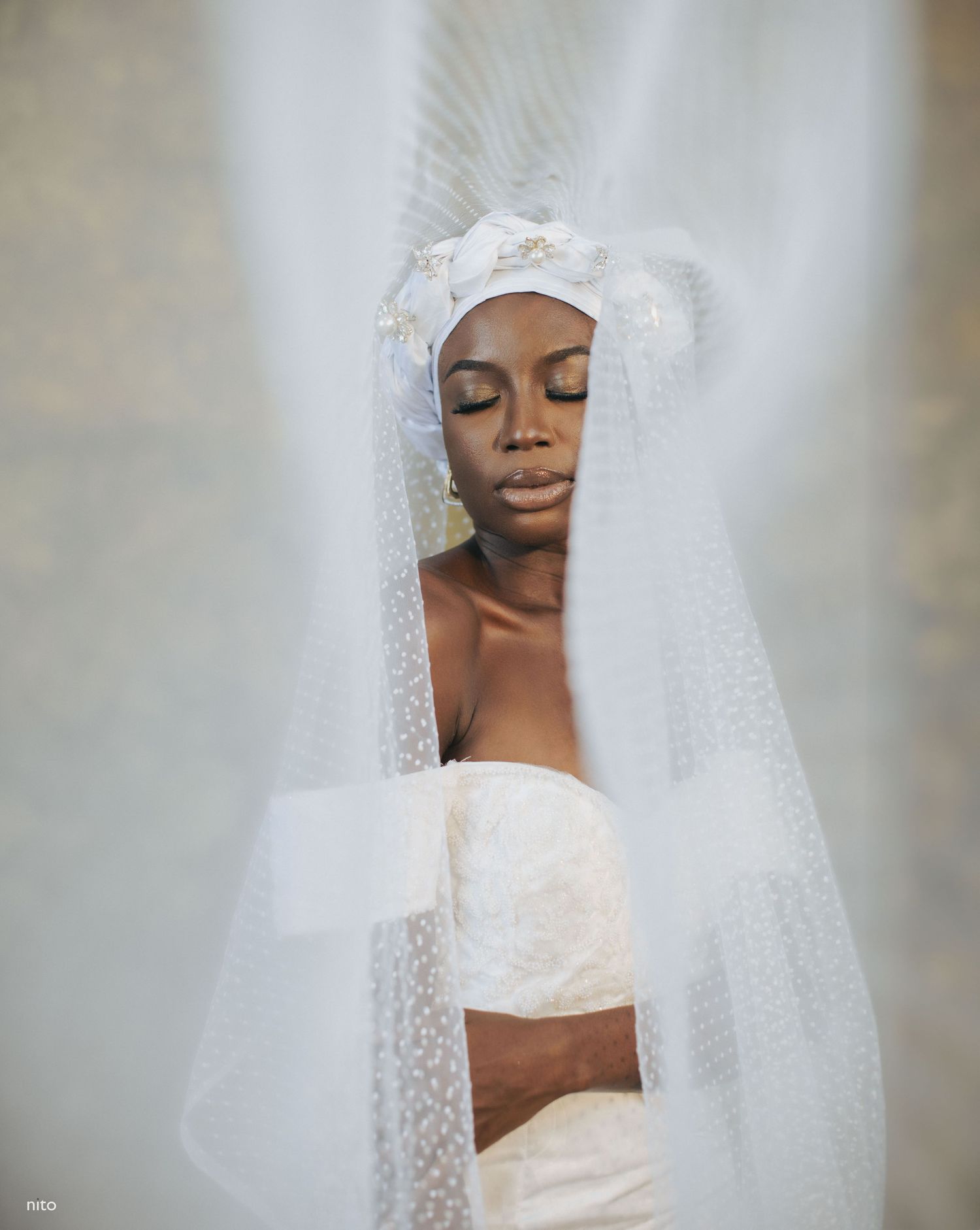 Serene bridal portrait with delicate white veil creating ethereal lighting effect.