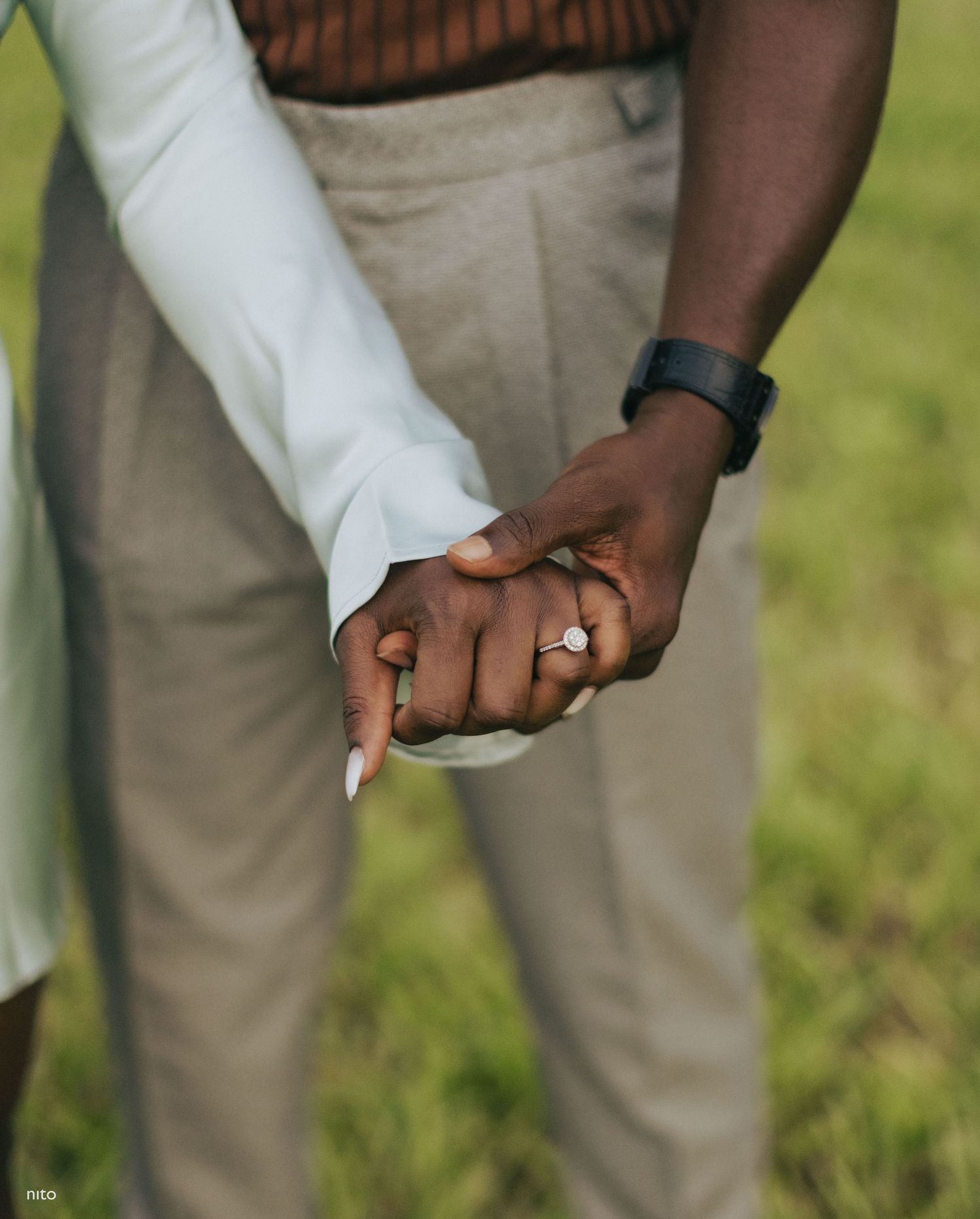 Close-up of clasped hands showing wedding rings against a light colored clothing background.