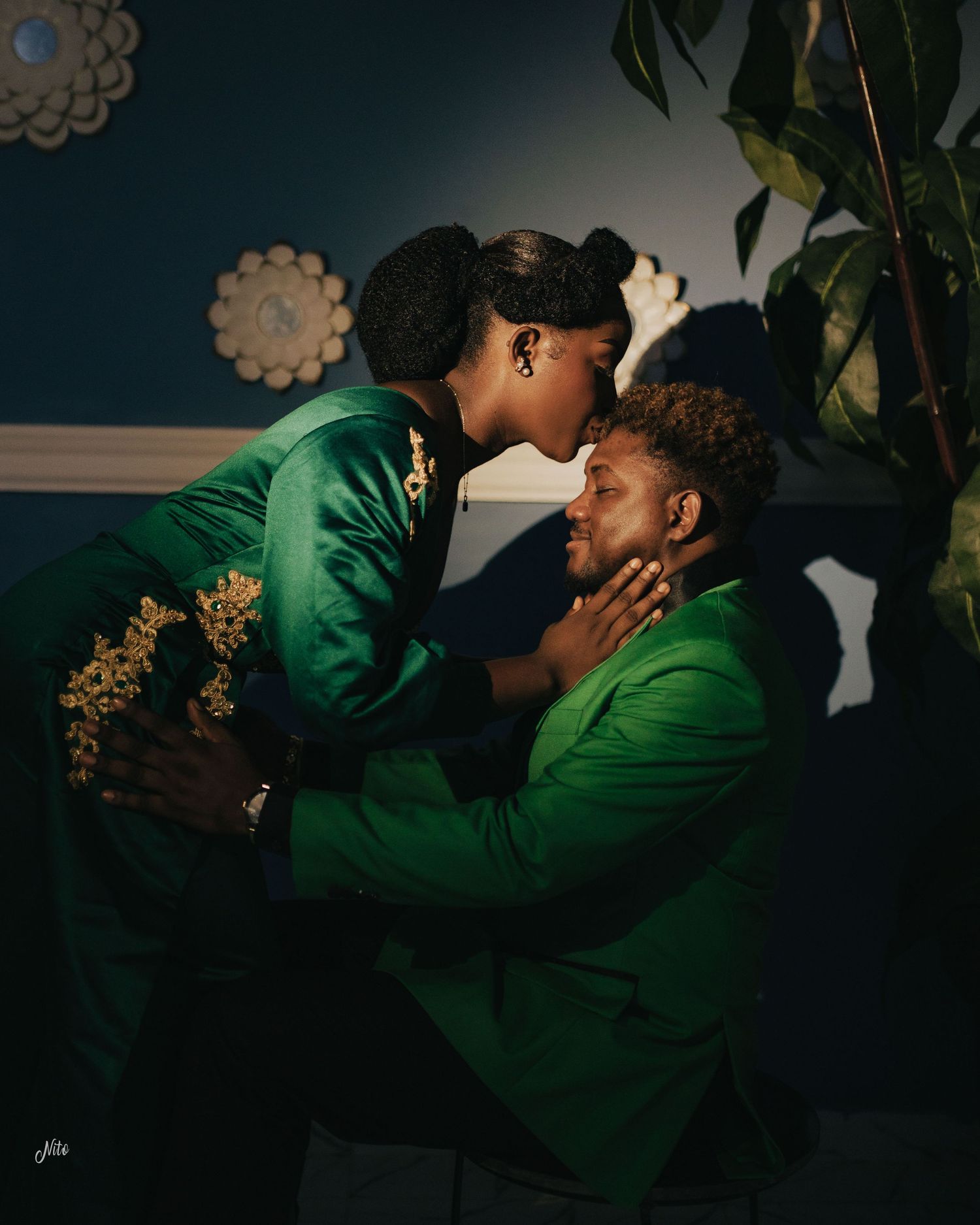 A tender intimate moment between two people wearing matching emerald green formal attire.