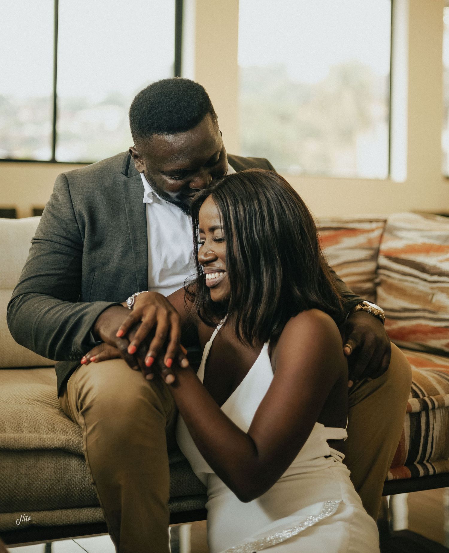 A tender moment between a couple sitting together on a brown couch.