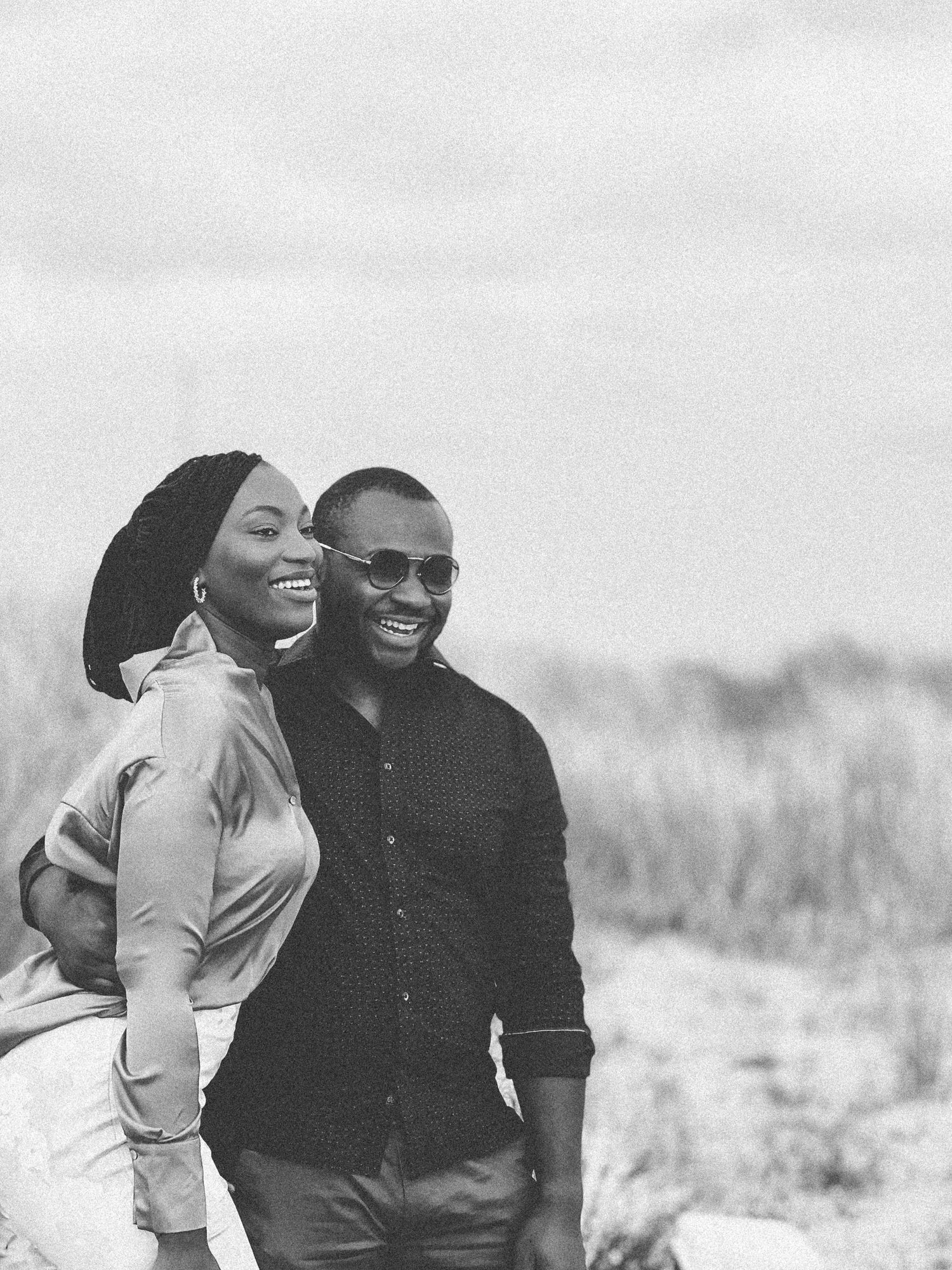 A joyful candid moment between a couple laughing together outdoors in black and white.