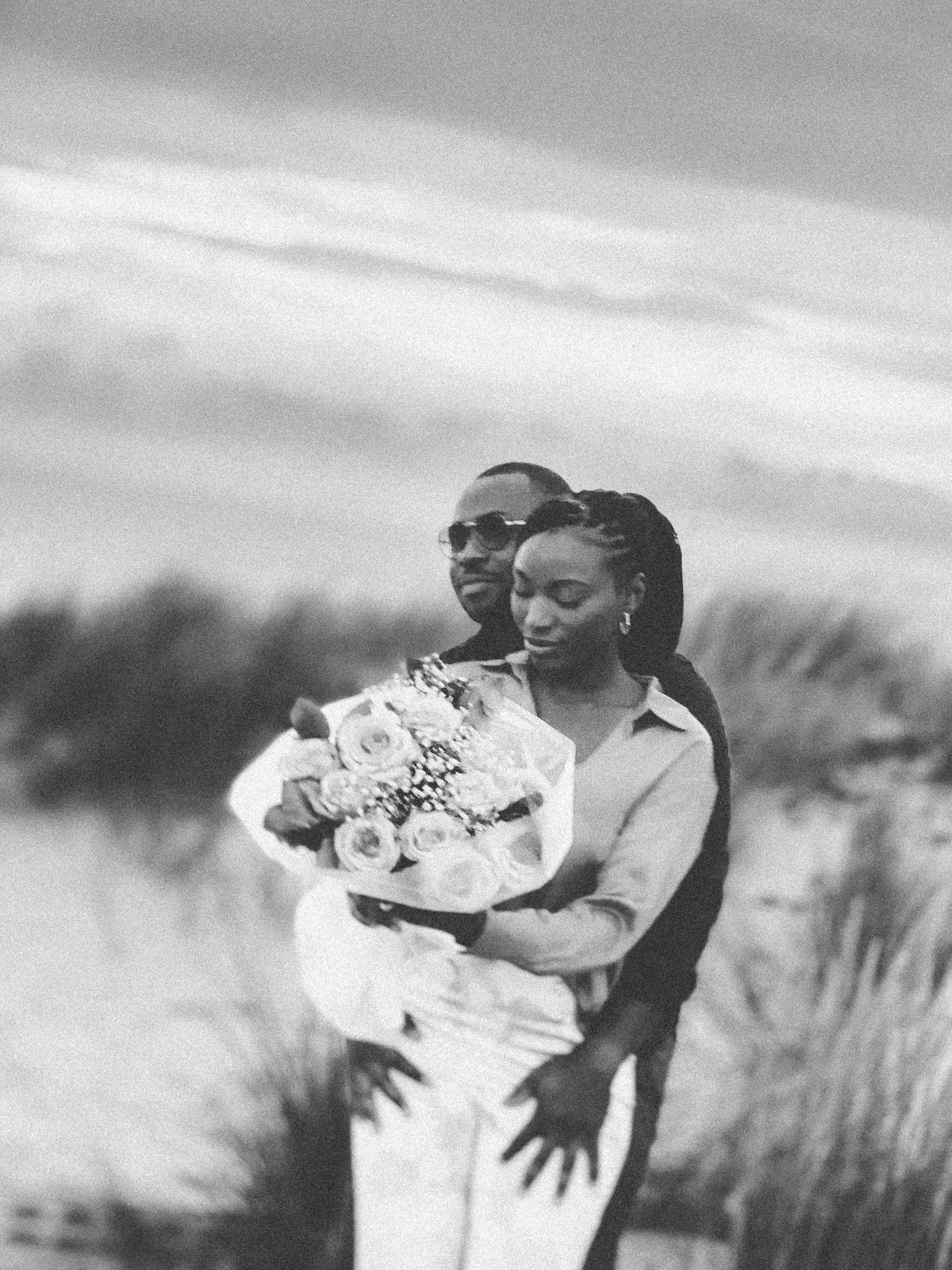 An intimate black and white photo of a couple sharing a close embrace with roses.