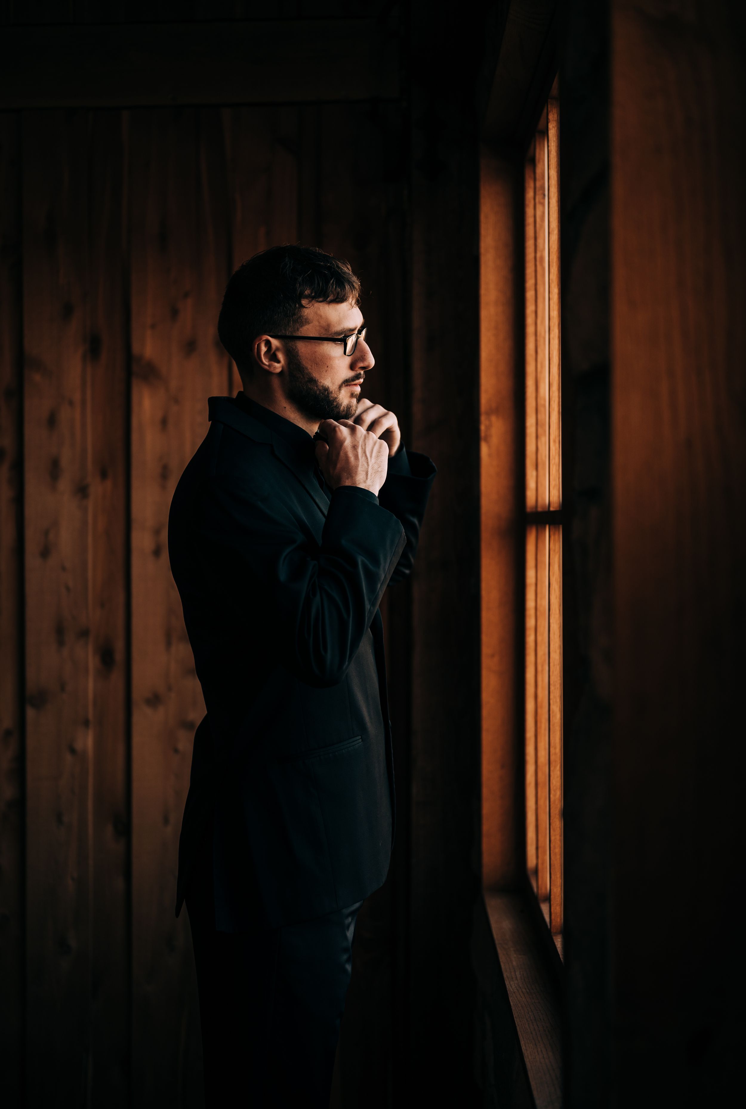 Groom adjusting next to window