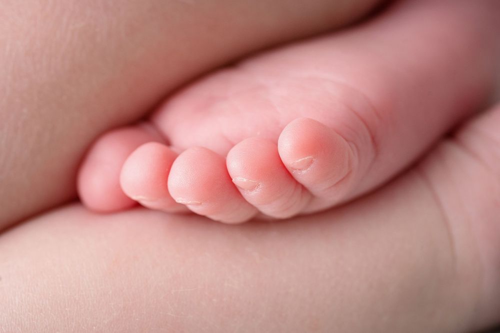 Close-up of tiny pink baby toes against soft fabric background.