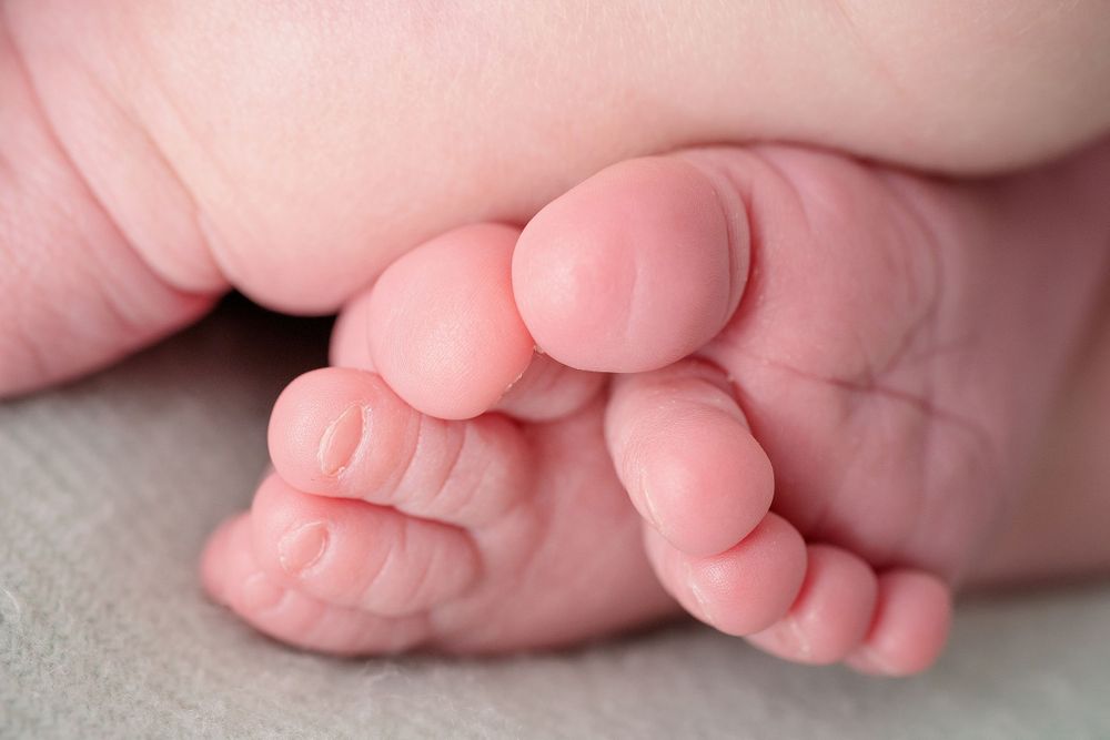 Detail shot of infant's tiny feet with delicate toes against soft fabric.