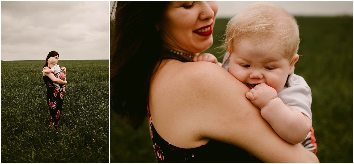 A woman and baby share intimate moments in a field under cloudy skies.