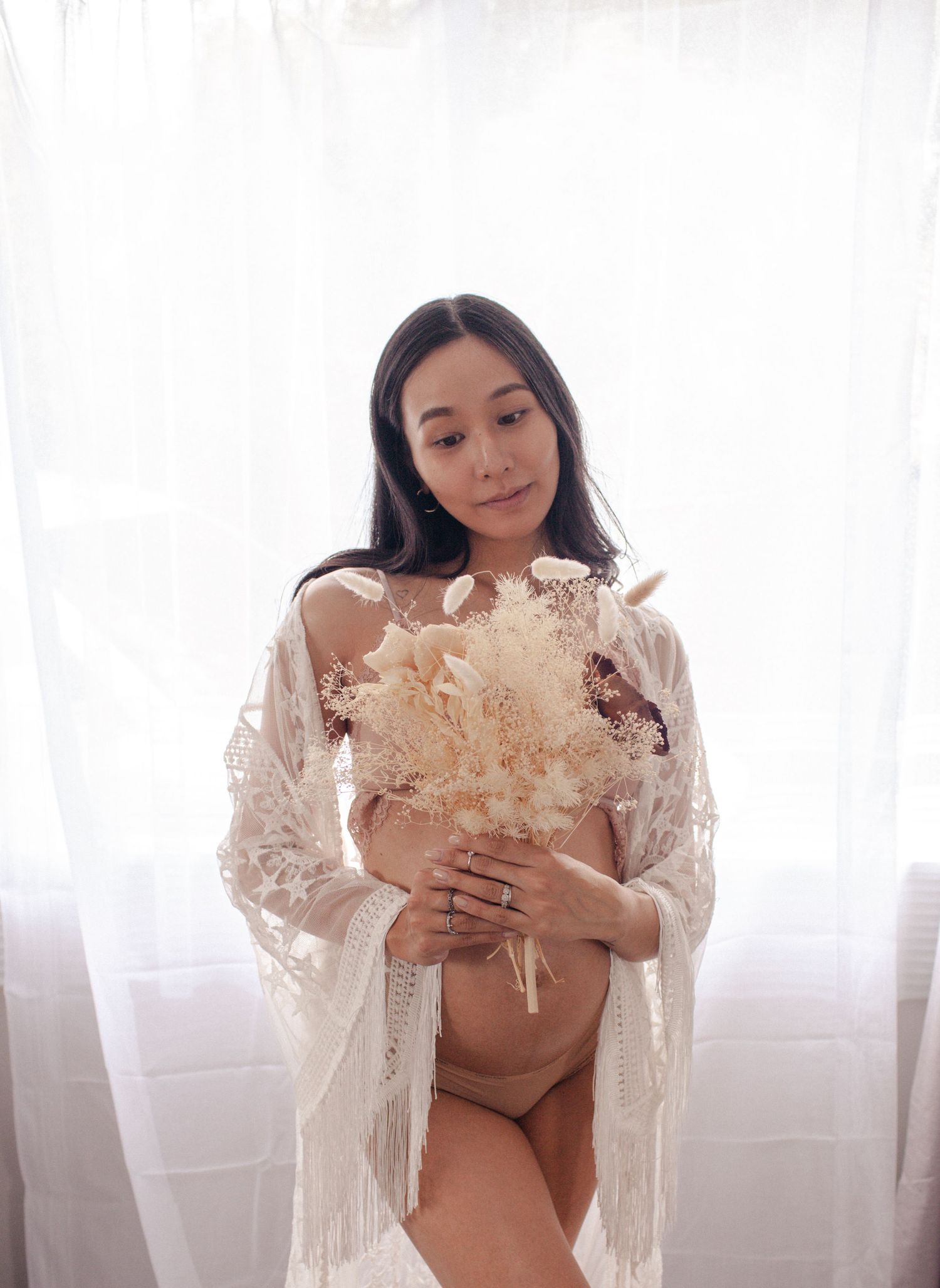 Intimate maternity portrait with dried pampas grass and lace robe in bright setting.