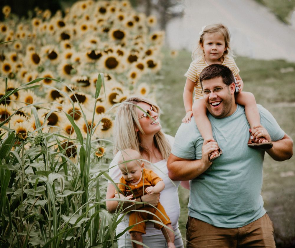 A candid image of a family walking through a sunflower field.