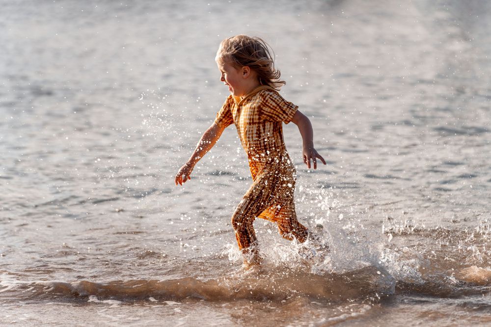 kid running in the water during family photoshoot in Northern Beaches Sydney