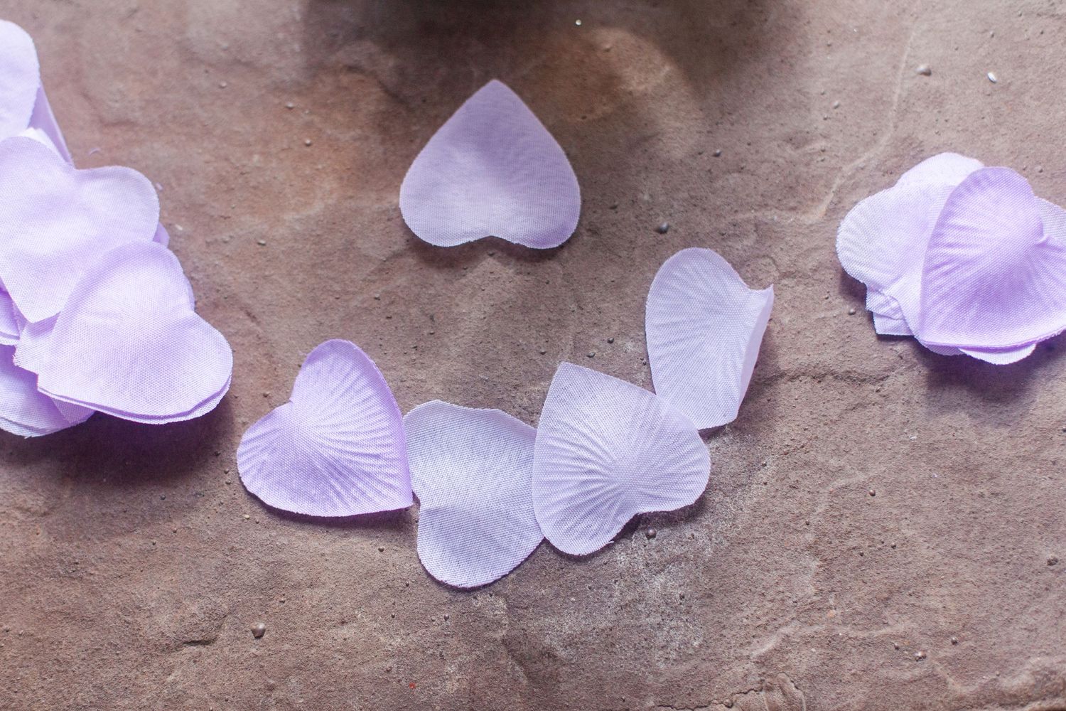 Delicate purple and white paper butterflies scattered on a textured surface.