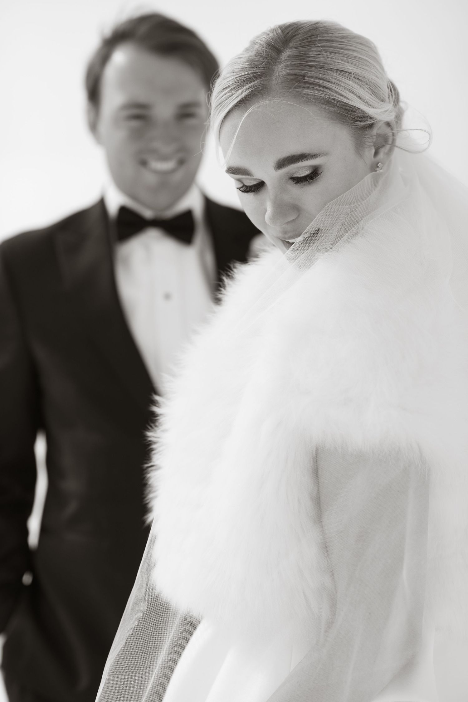 black and white portrait of a bride in a white fur and chic updo and a groom in a classic tuxedo in Aspen, Colorado