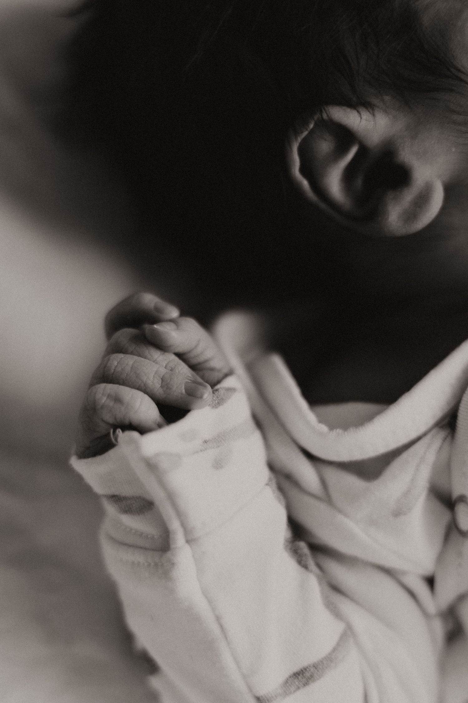 Close up black and white photo of tiny newborn hand grasping.