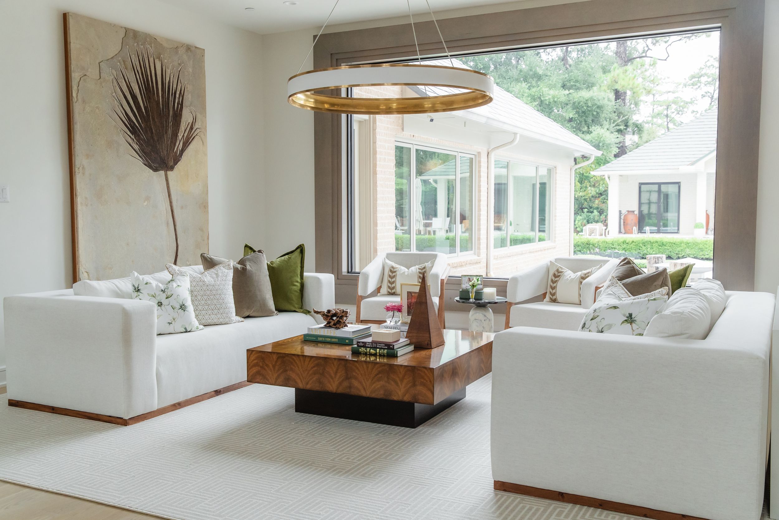 Modern living room with white sofas, wooden center table and contemporary lighting fixture.