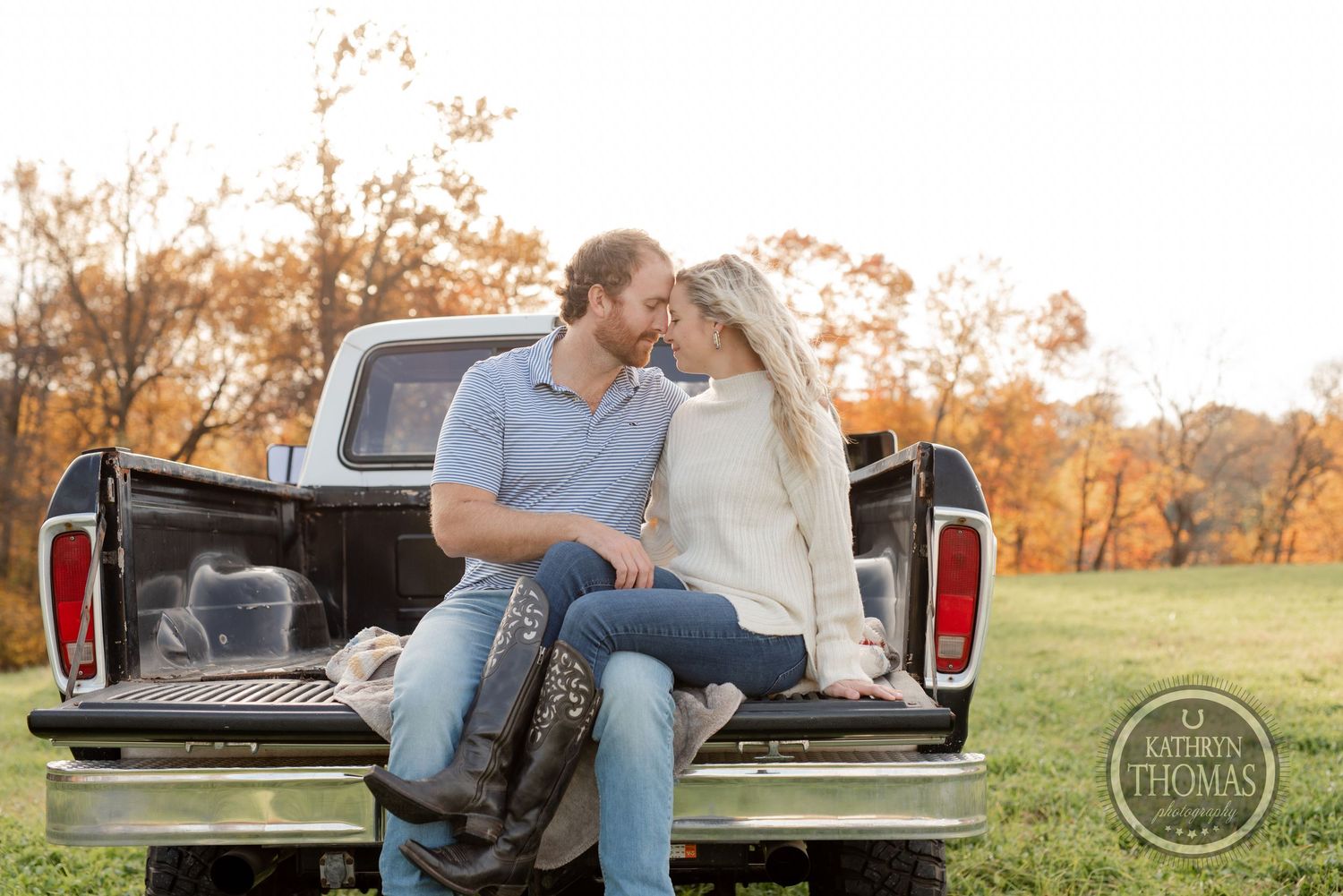 Romantic couple sharing intimate moment on back of classic pickup truck in fall setting.
