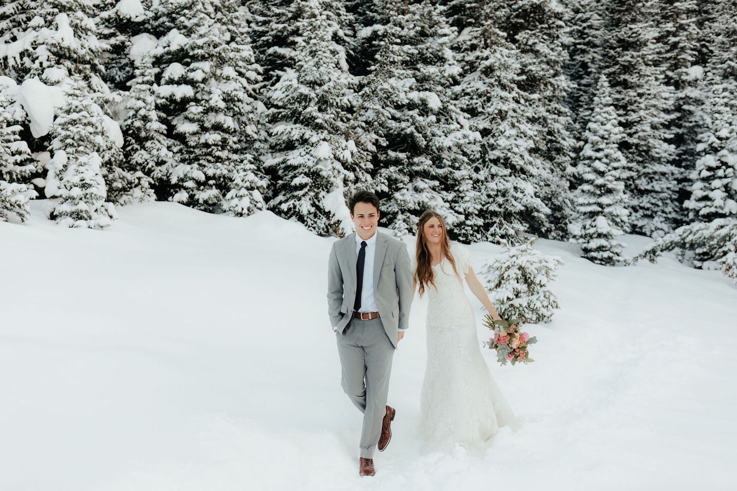 Bride and Groom walking through deep mountain snow