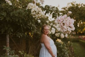 Romantic garden scene with white flowers and flowing dress against lush greenery at golden hour.