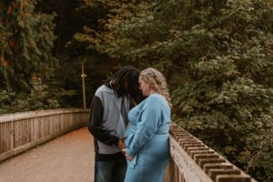 A couple shares joyful moments on a wooden deck surrounded by autumn foliage.