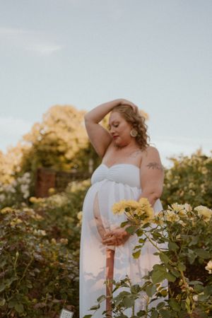 Soft sunlit garden portrait with white dress among blooming flowers.