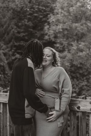 Two people embrace and laugh together on a wooden deck during an autumn photoshoot.