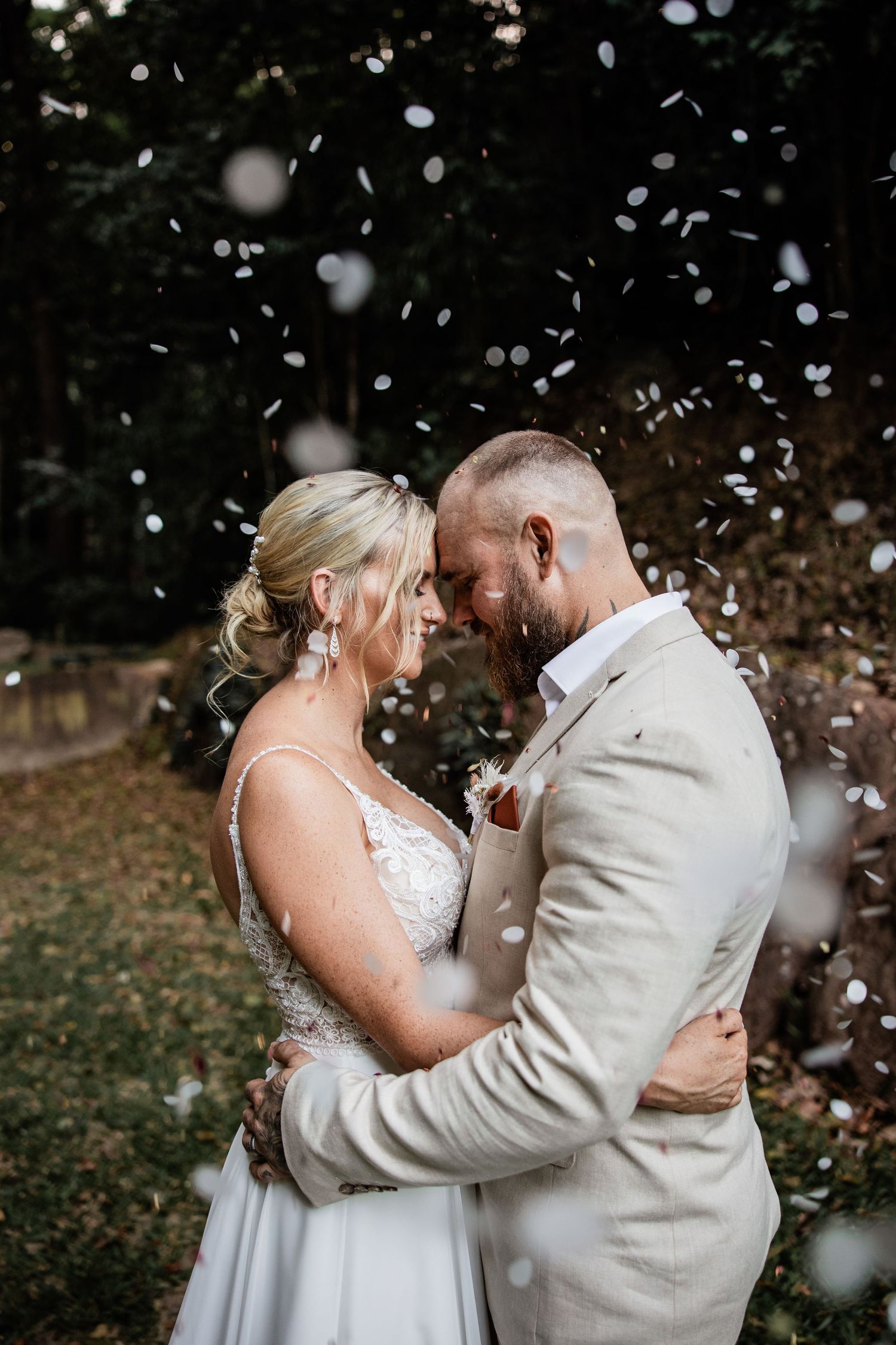 Couple embraces in romantic moment as confetti falls around them during wedding celebration.