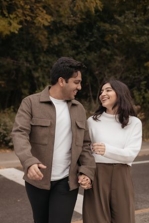 A couple shares joyful laughter while walking together on an autumn day.