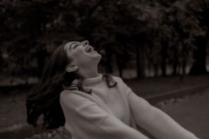 Woman in white sweater enjoying carefree moment outdoors with hair flowing.