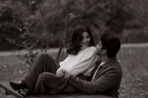 A tender black and white portrait of a couple resting together outdoors.