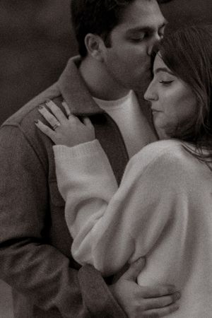 An intimate black and white portrait capturing a tender moment between two people.
