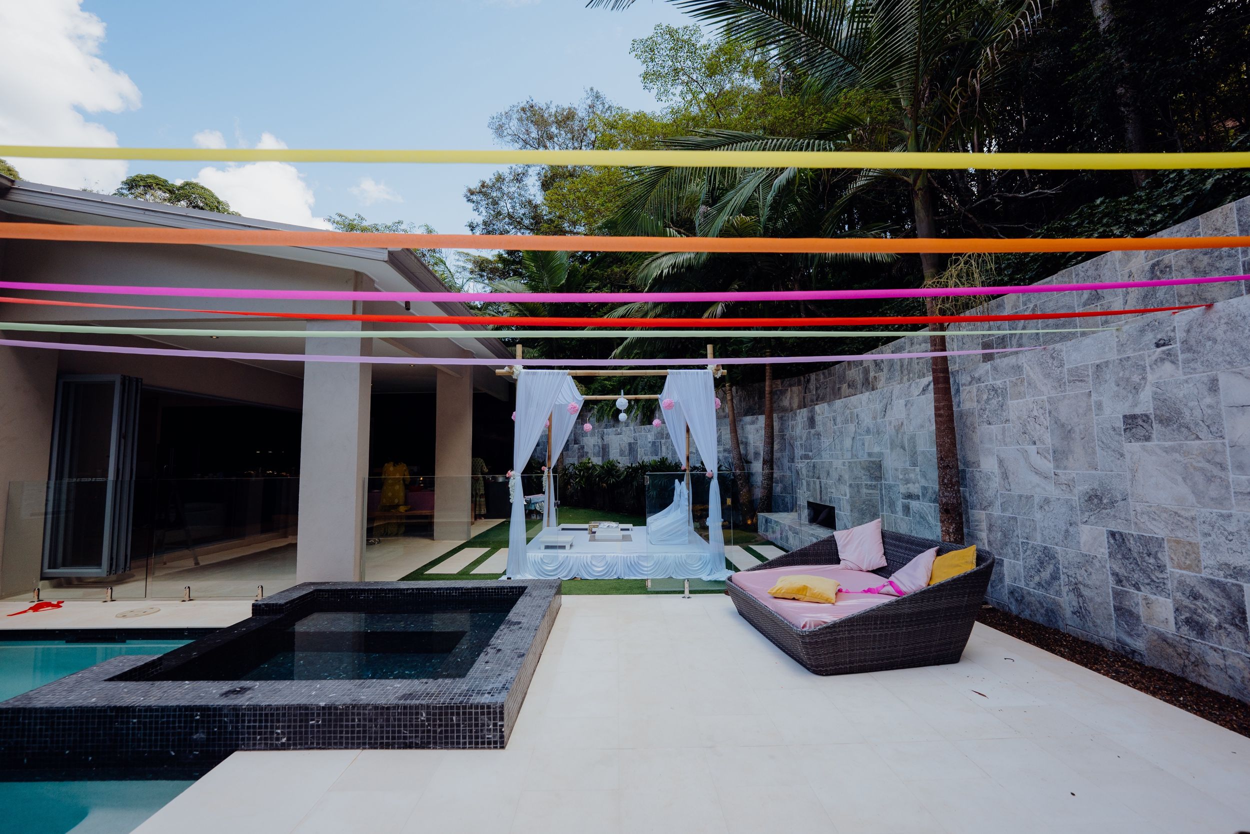 Modern poolside area with colorful striped overhead canopy and lounge seating.