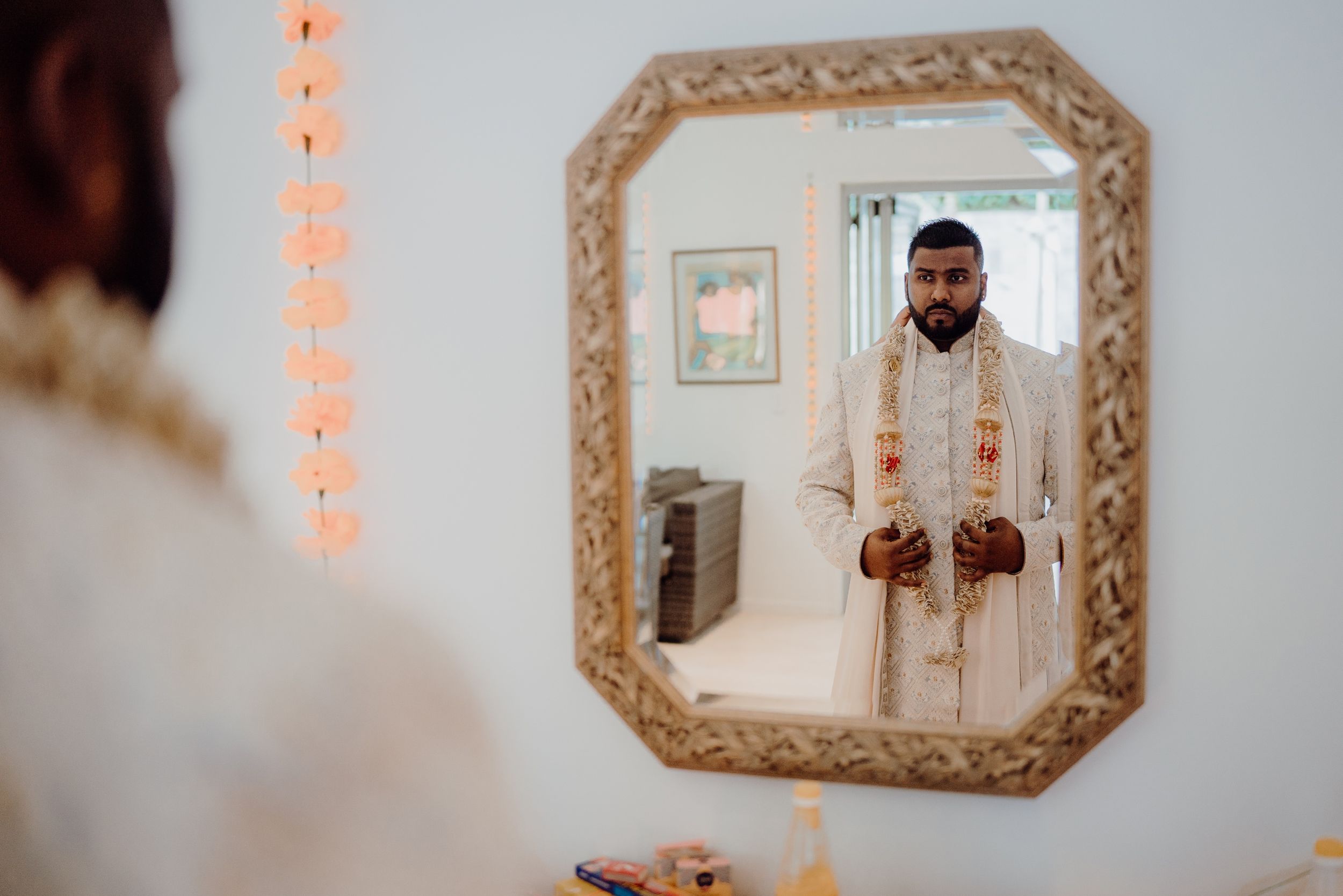 Reflection in ornate gold mirror frame showing formal attire and interior decor.