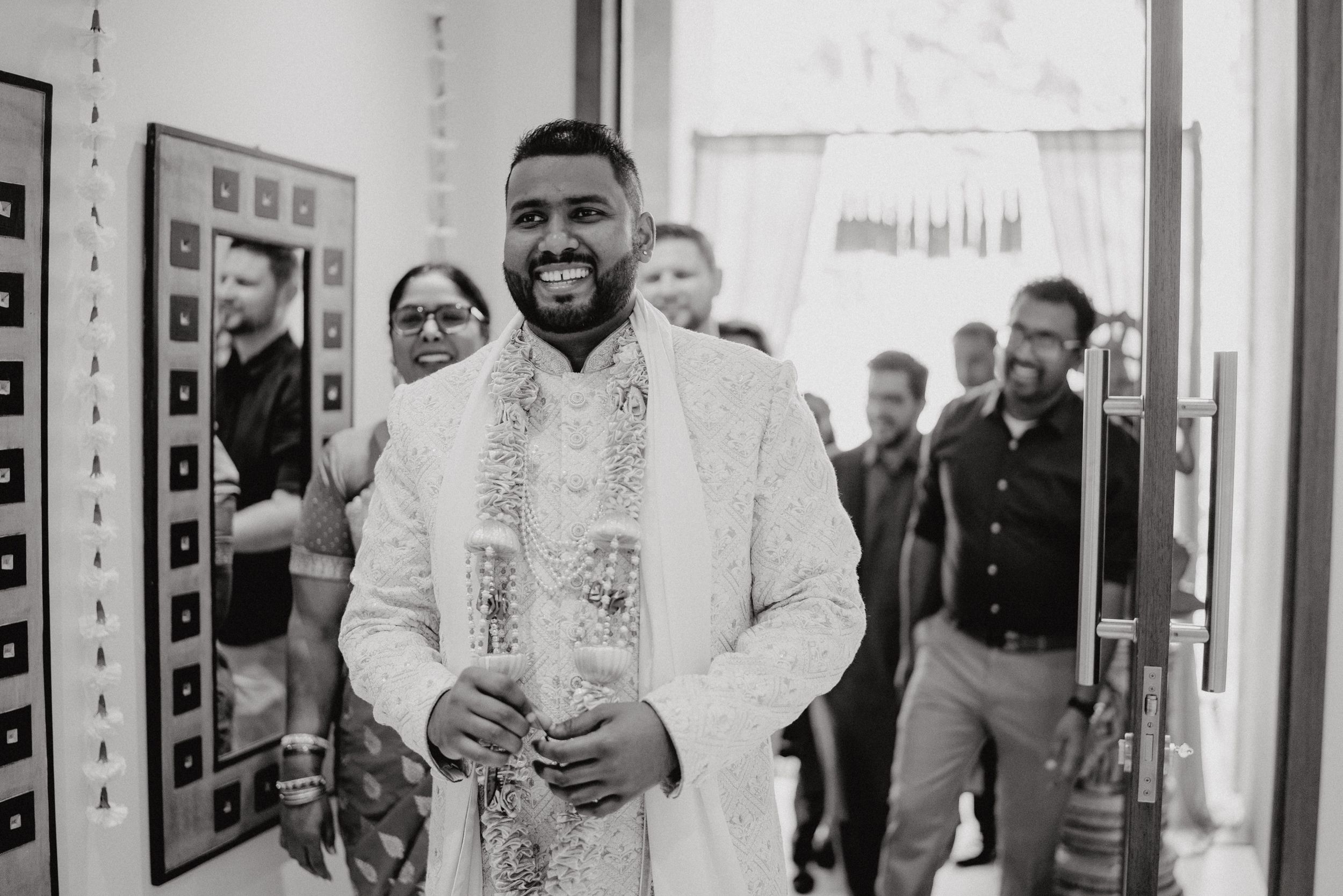 A joyful moment captured in a hallway during a cultural celebration with guests looking on.