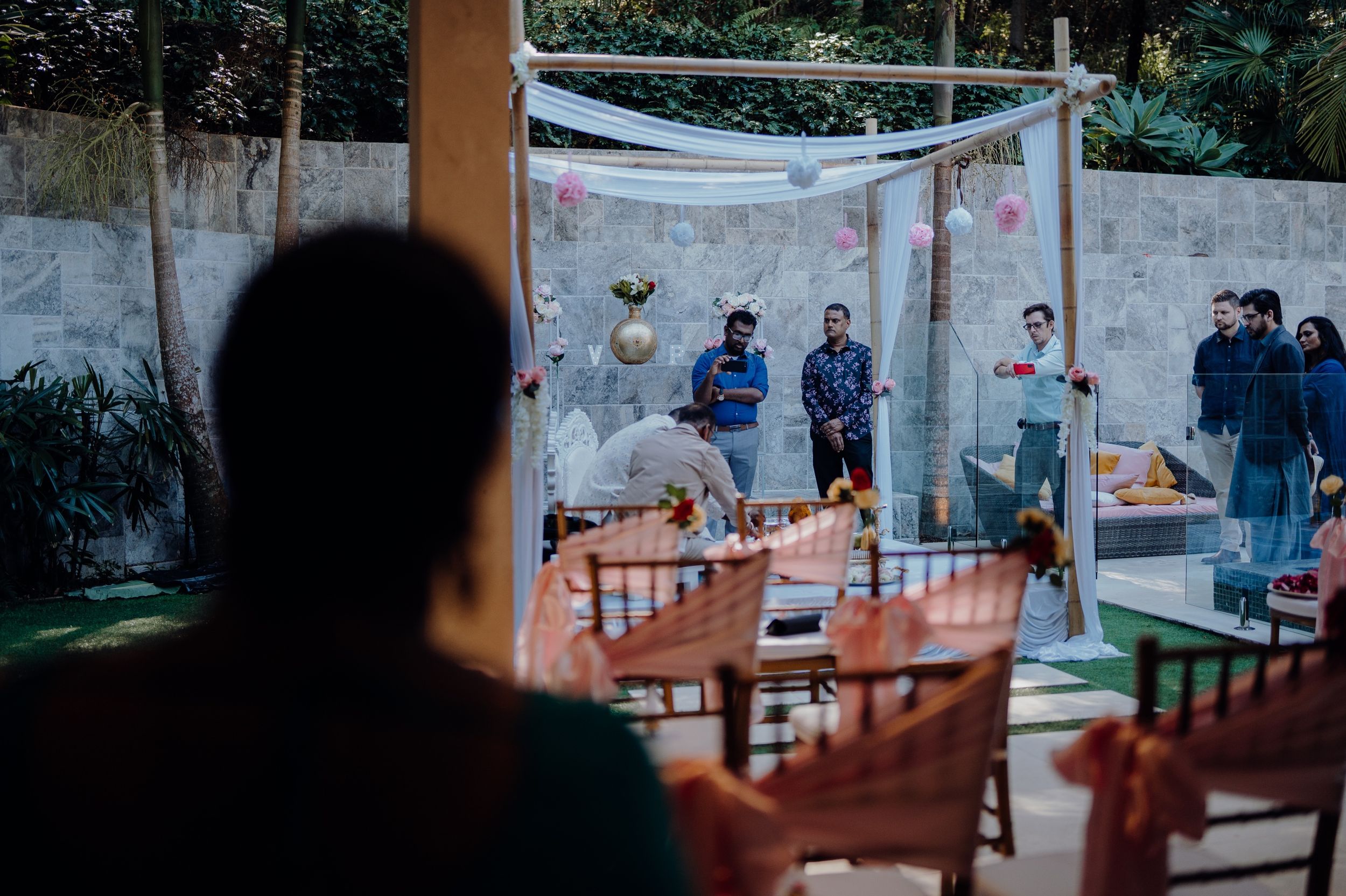 An outdoor wedding ceremony setup viewed through a silhouette with chairs and decorative canopy.