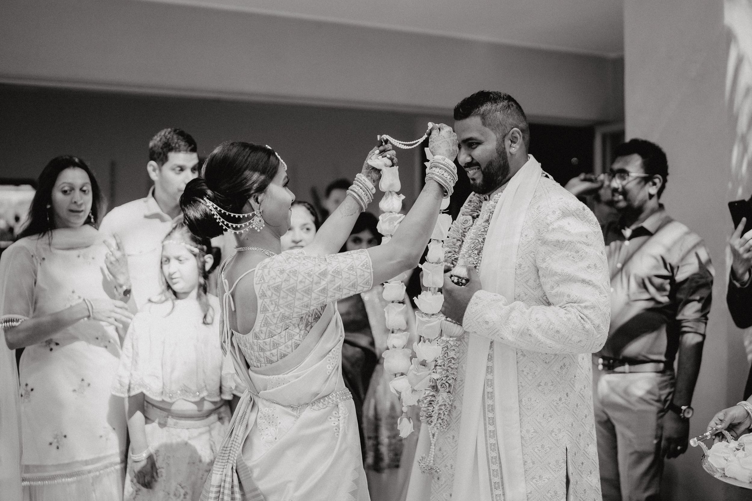 Black and white photo of a traditional wedding ceremony with flower petals being showered on the couple.
