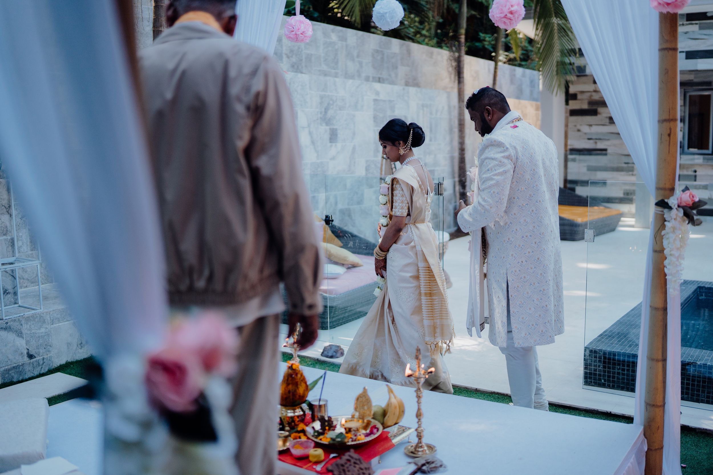 Intimate outdoor wedding ceremony setup with white drapes and traditional decor elements.